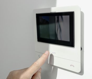 Intercom in home interior and a hand ready to open the door button